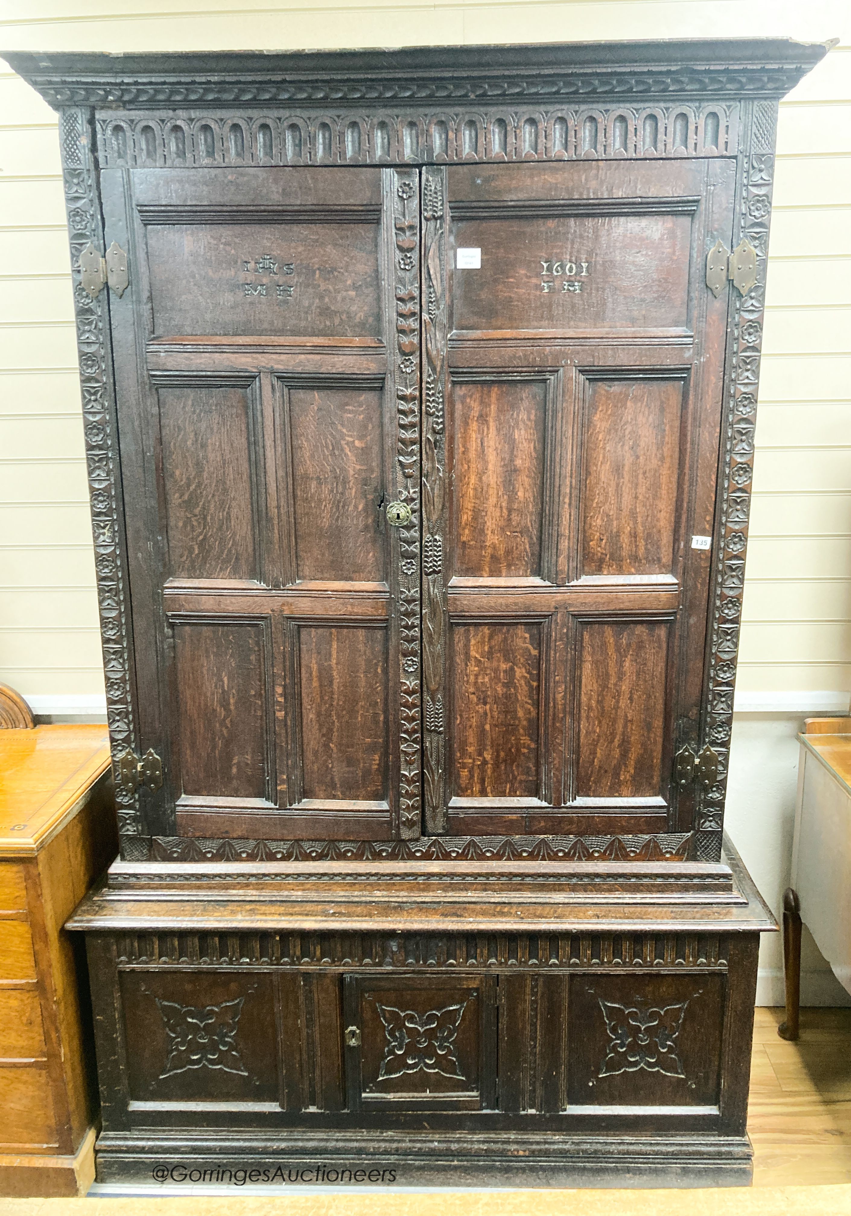 A carved oak cupboard, enclosed by panelled doors, bearing monograms and dated 1601, width 138cm, depth 53cm, height 218cm